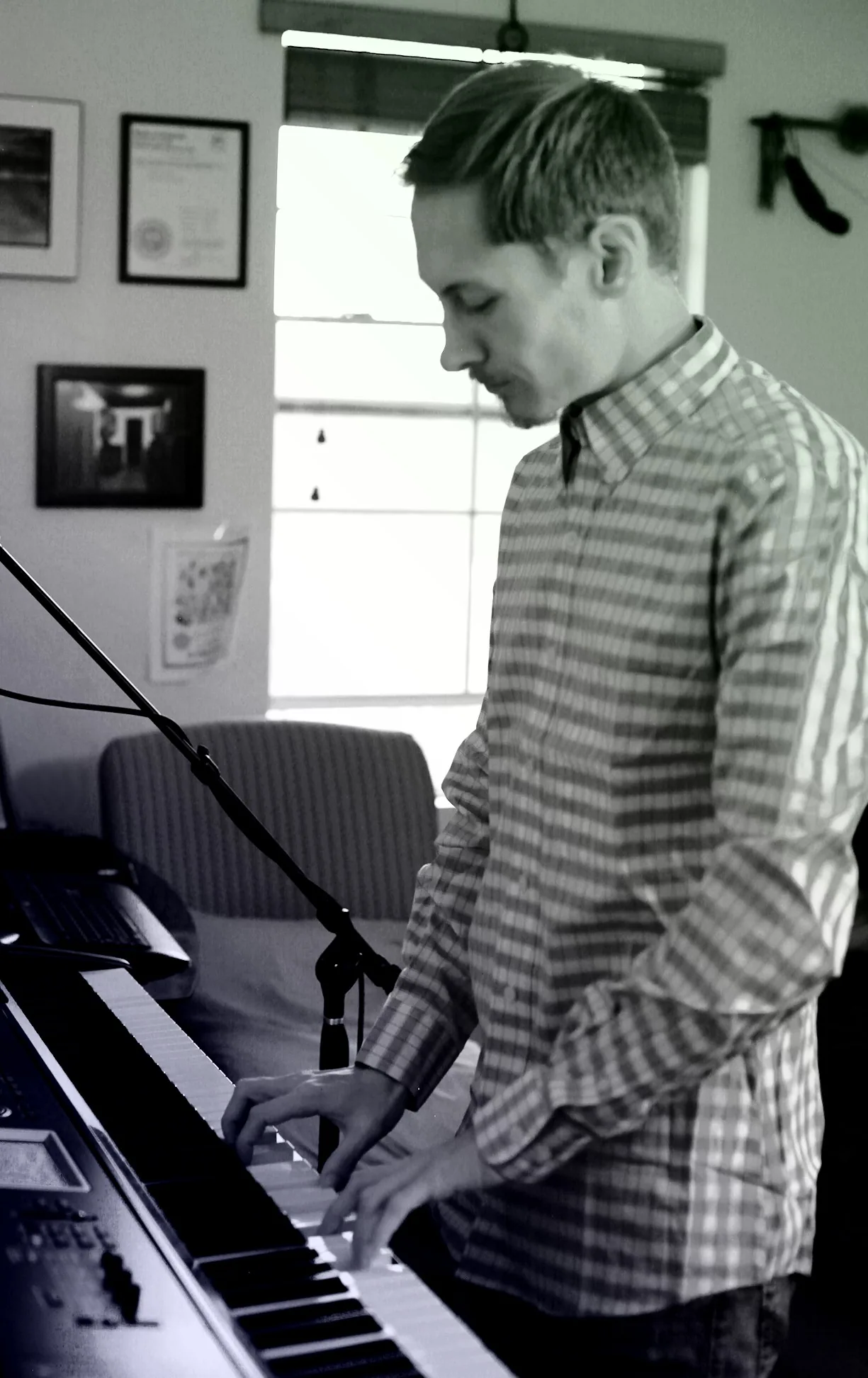 Black-and-white vertical portrait of Ryan performing on a keyboard