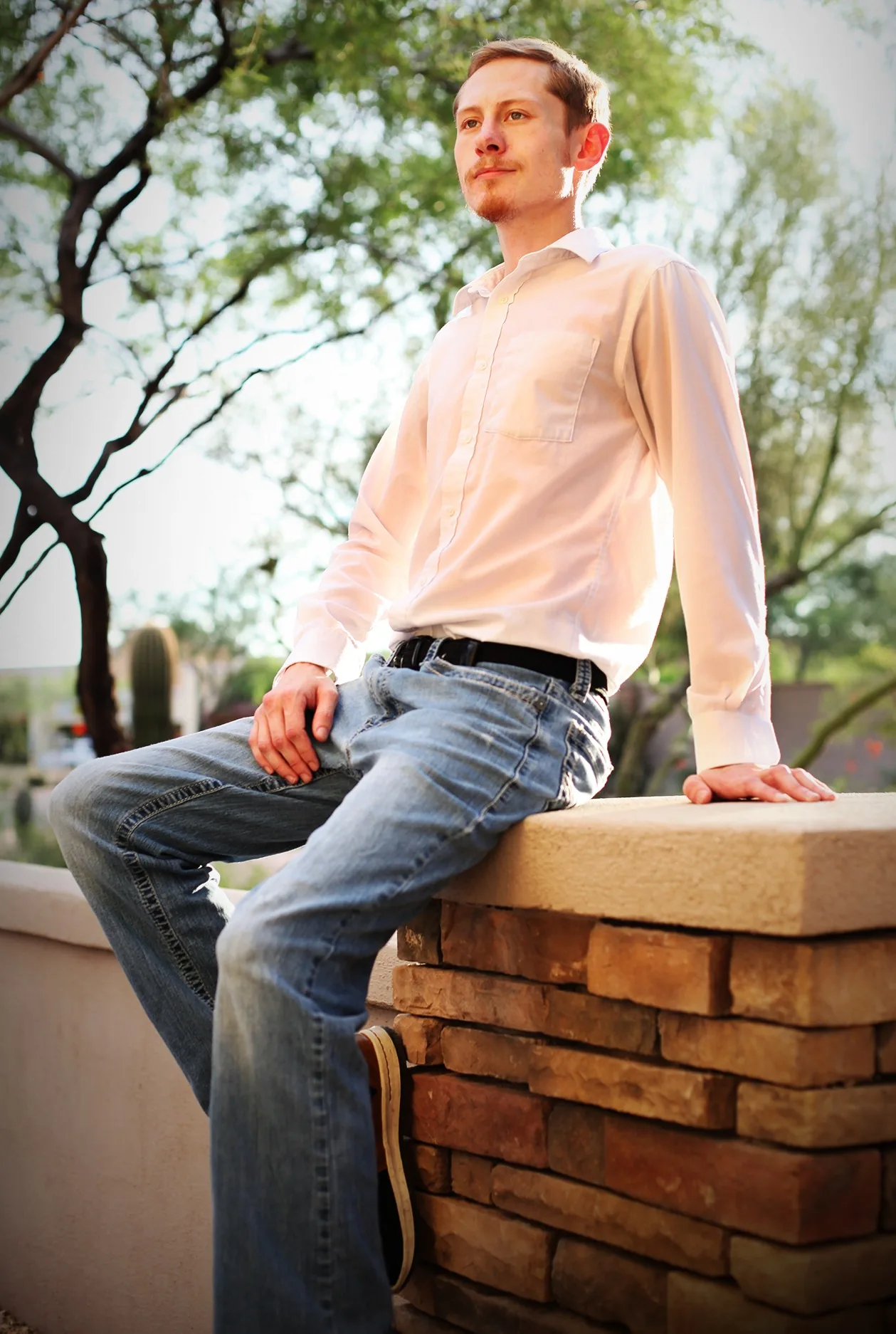 Ryan seated on a stone wall in warm backlight